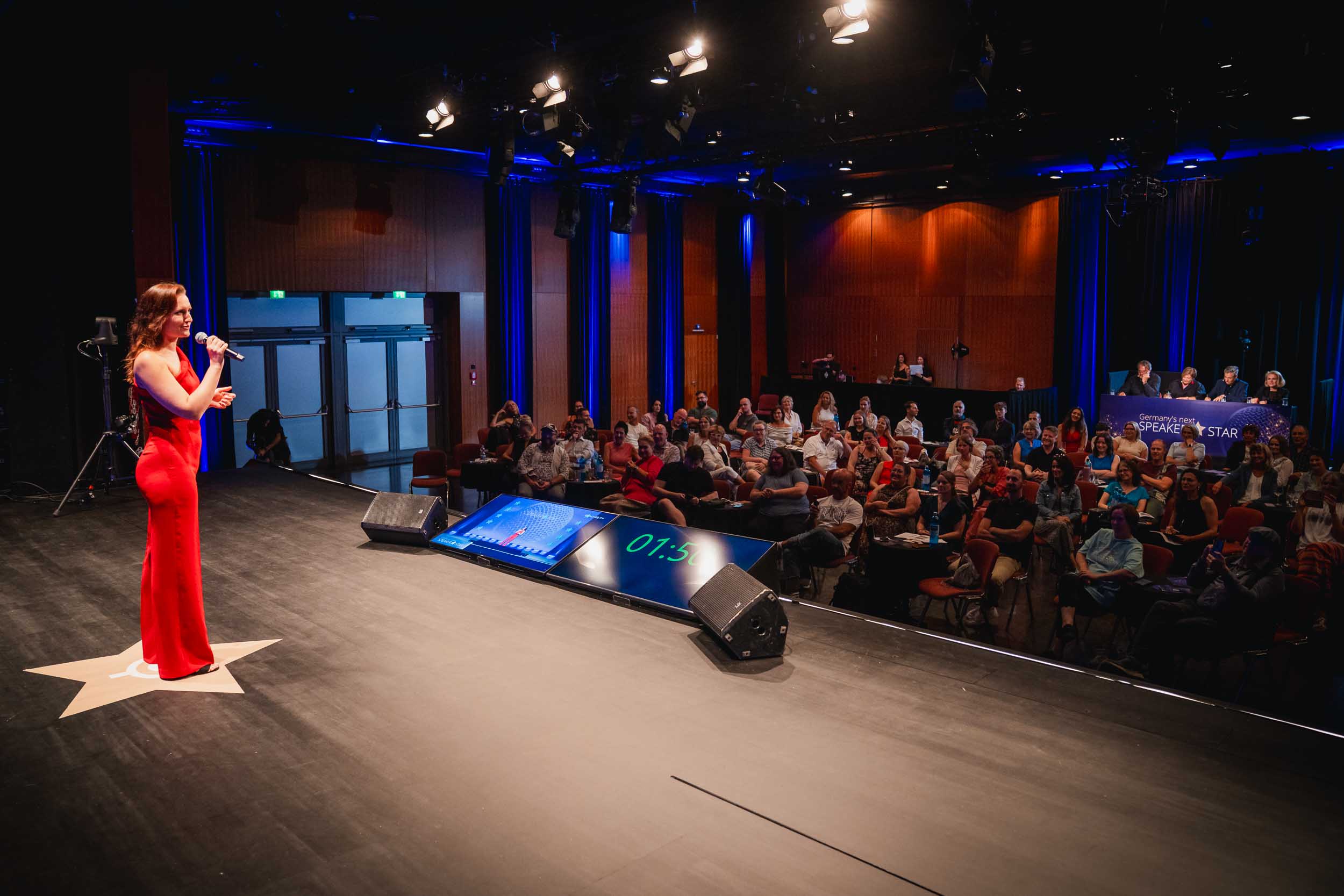 Viviane Albert spricht auf der Bühne beim Wettbewerb Germany's Next Speaker Star vor vollem Publikum
